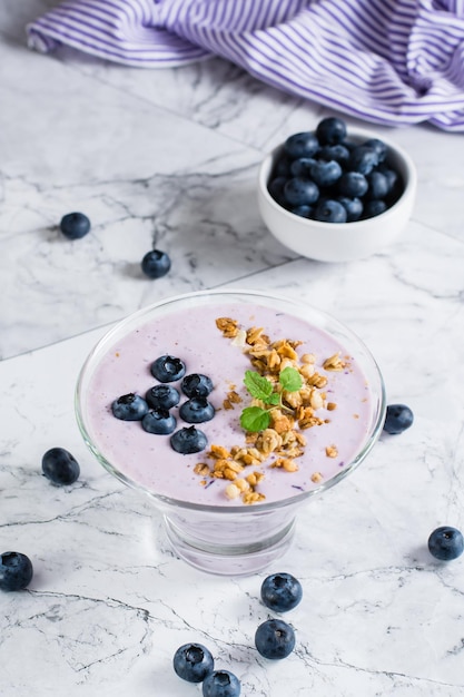 Tazón de batido con arándanos y granola en la mesa Alimentos orgánicos antioxidantes Vista vertical