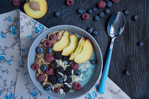 Tazón de batido con bayas frescas, semillas de chía, frutas y almendras. Un conjunto de bayas frambuesa, durazno, arándanos. Desayuno saludable.