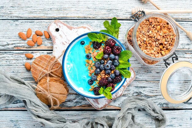 Tazón de batido de espirulina azul y frutas frescas Cubierto con moras, arándanos, granola y yogur Desayuno Vista superior Espacio libre para el texto