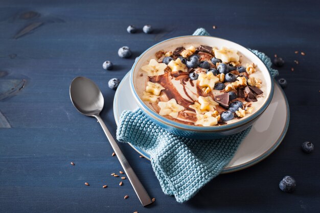 Tazón de batido de plátano saludable con nueces de chocolate con arándanos