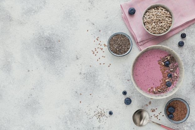 Tazón de batido de yogur rosa hecho con arándanos frescos y semillas