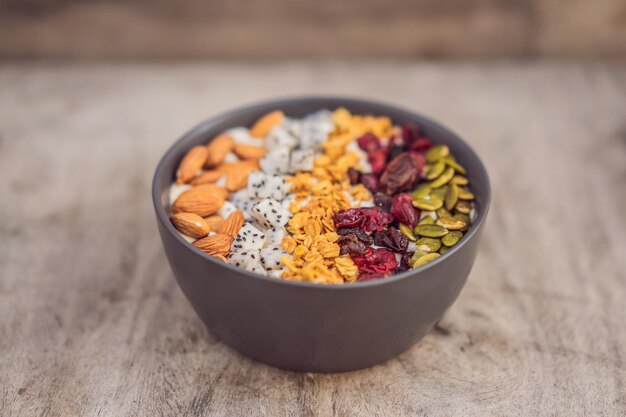 Tazón de batidos de mango con almendras dragon fruit cerezas secas semillas de calabaza y granola sobre fondo de madera