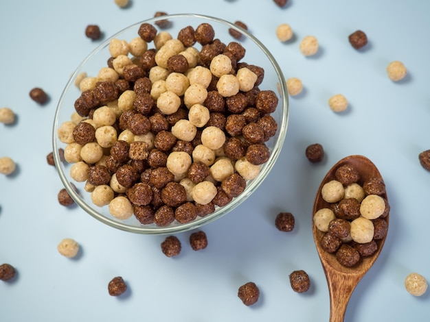 Tazón con bolas de cereal de chocolate sobre un fondo azul Concepto de desayuno saludable
