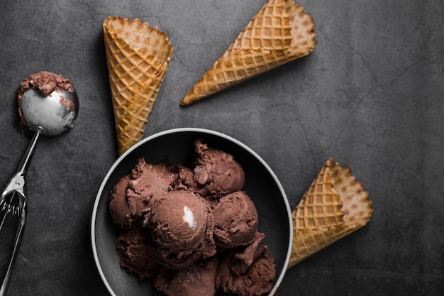 Tazón con bolas de helado al lado de conos de helado