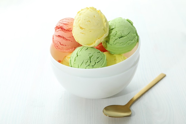 Tazón con bolas de helado en la mesa de madera blanca