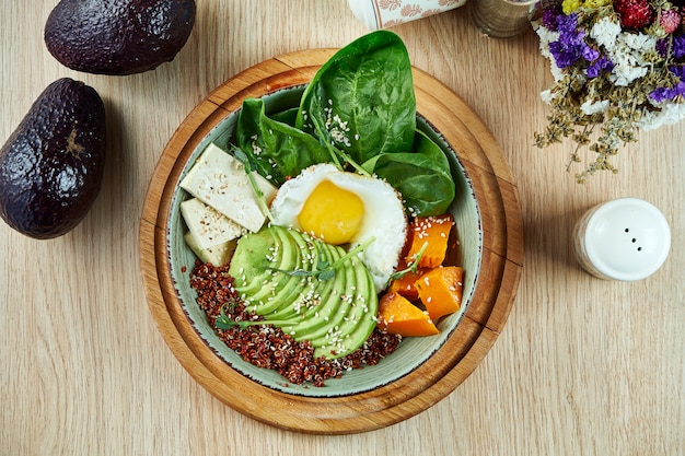 Tazón de Buda con quinua, calabaza, espinacas, queso de soja y huevo frito. Comida sana y equilibrada. Nutrición fitness. Vista superior, comida plana.