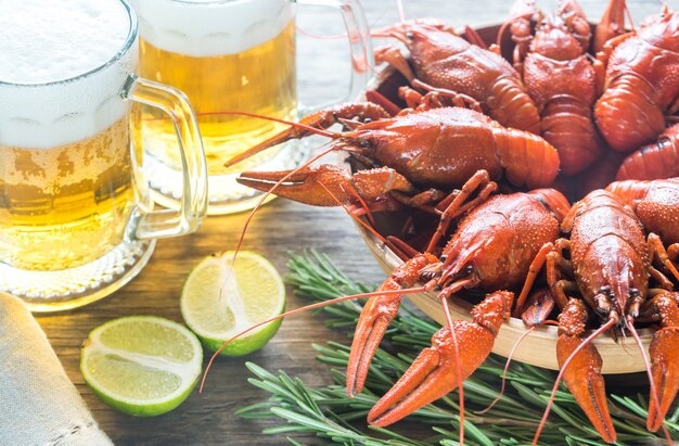 Tazón de cangrejo hervido con dos jarras de cerveza