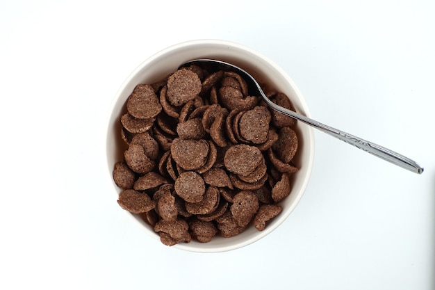 Un tazón de cereal con una cuchara dentro y una cuchara dentro.