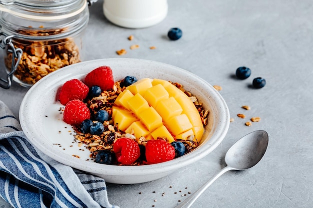 Tazón de cereal de desayuno saludable granola casera con arándanos frescos, frambuesa y mango