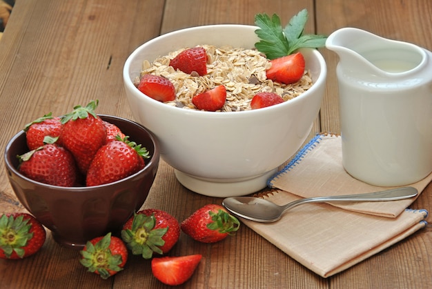 Tazón de cereal con leche y fresas en mesa de madera