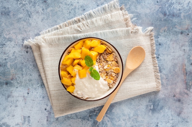 Tazón de cereal con mango y yogur, vista superior
