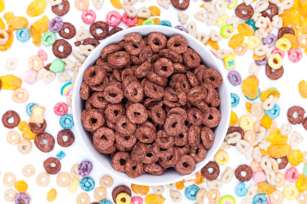 Foto tazón de cereales de chocolate y cereales esparcidos por la mesa