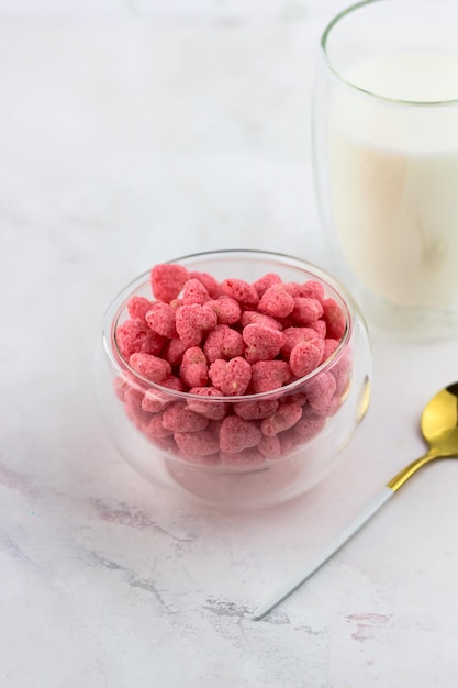 Un tazón de cereales para el desayuno y un vaso de leche sobre un fondo de mármol blanco Aperitivos con sabor a frambuesa