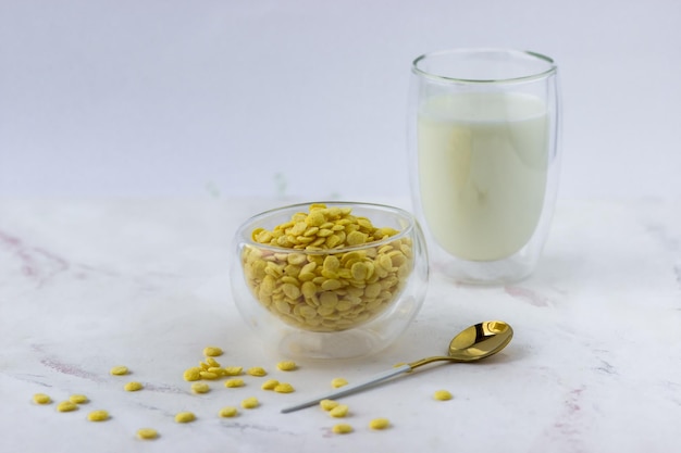 Un tazón de cereales para el desayuno y un vaso de leche sobre una mesa de mármol blanco Copos de maíz instantáneos