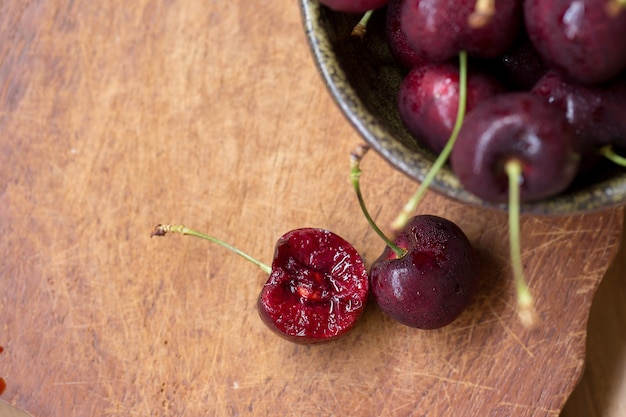 Tazón de cerezas. Cerezas rojas en un recipiente en el fondo de madera