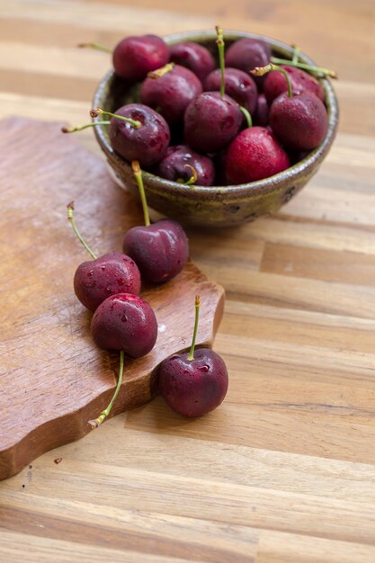 Tazón de cerezas. Cerezas rojas en un recipiente sobre fondo de madera