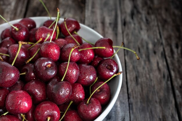 Tazón de cerezas rojas frescas en madera