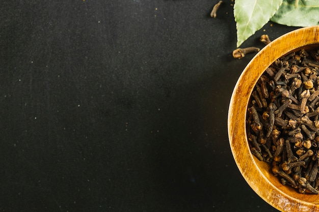 Foto tazón con clavos cerca de hojas de laurel