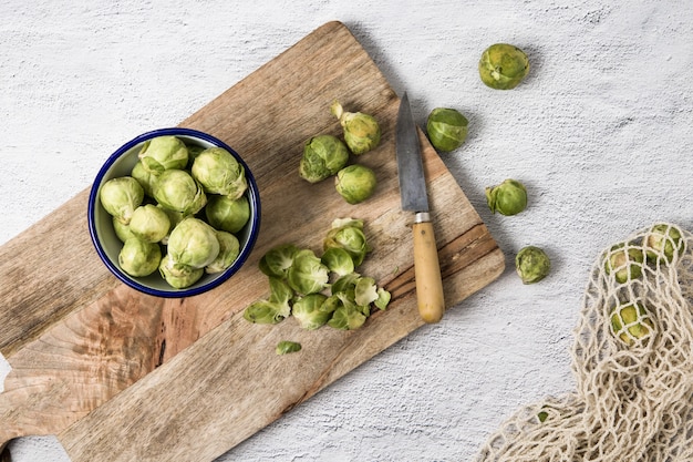 Foto un tazón con coles de bruselas sobre una tabla para cortar madera