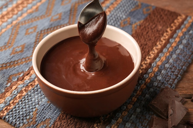 Tazón con deliciosa salsa de chocolate derretida y cuchara en la mesa