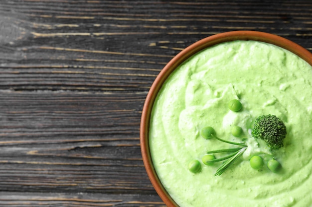 Tazón con deliciosa sopa de brócoli sobre fondo de madera