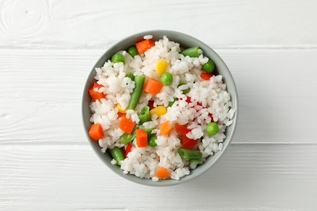 Tazón de delicioso arroz con verduras sobre superficie de madera