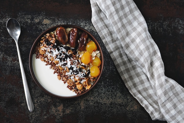 Tazón de desayuno con yogur griego, avena, granola y frutos secos.
