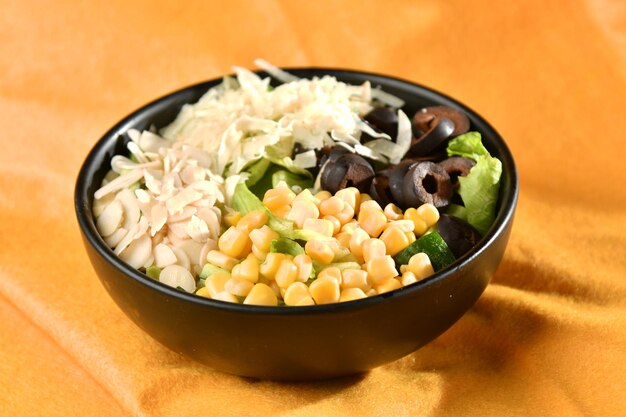 Un tazón de ensalada con aguacate, aceitunas negras y aceitunas negras.