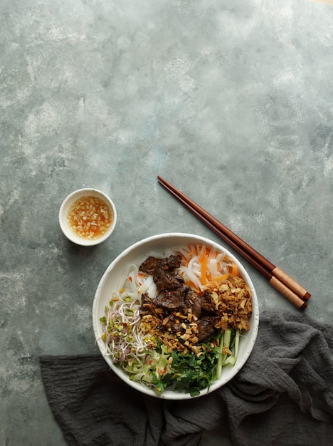 Tazón de ensalada de fideos vietnamita tradicional - Bun Bo Nam Bo, con carne de res, fideos de arroz, hierbas frescas, verduras en escabeche y salsa de pescado