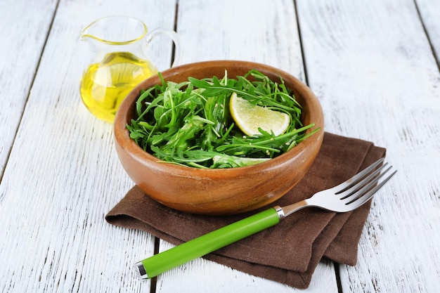 Tazón de ensalada verde y rodajas de limón sobre fondo de madera