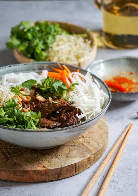 Tazón de ensalada vietnamita tradicional Bun Bo Nam Bo con fideos de arroz con carne de res hierbas frescas verduras en escabeche y salsa de pescado