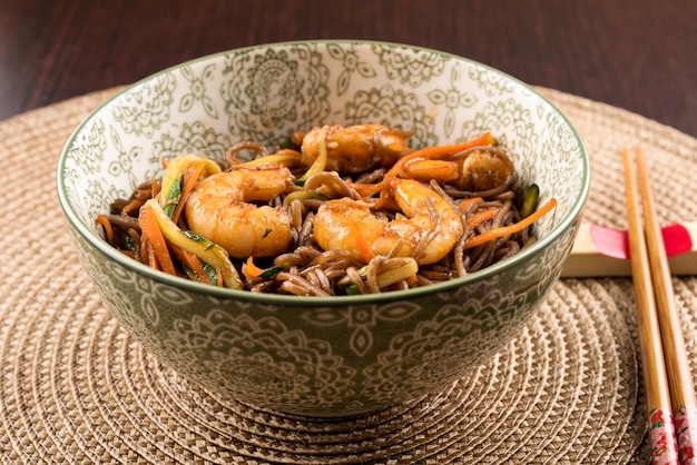 Tazón con fideos yakisoba con camarones colocados en la mesa