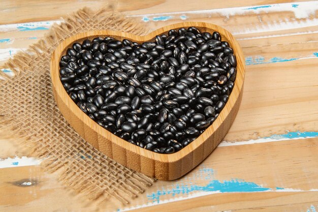 tazón de frijol negro en forma de corazón en una mesa de madera