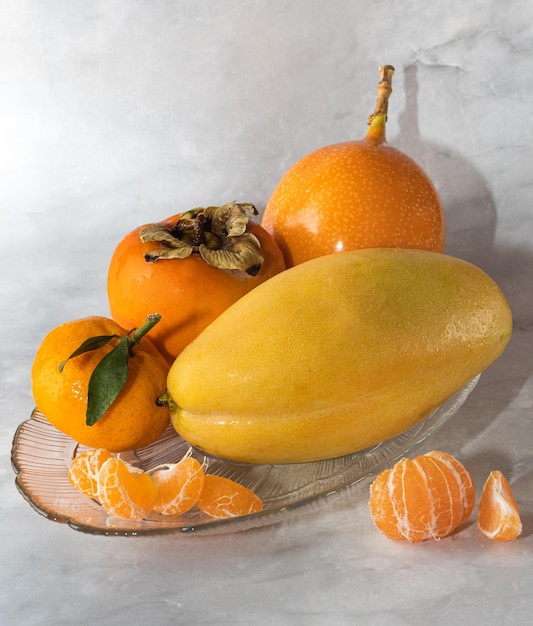 Un tazón de fruta mandarina, maracuyá, caqui y mango