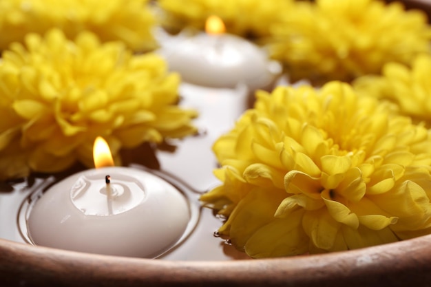 Tazón de fuente de agua de spa con flores y velas closeup