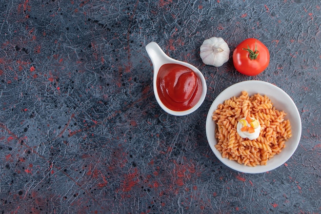 Tazón de fuente blanco de deliciosa pasta fusilli sobre fondo de mármol.