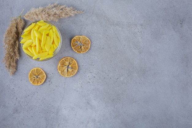 Tazón de fuente de caramelos dulces amarillos y limones en rodajas en piedra.