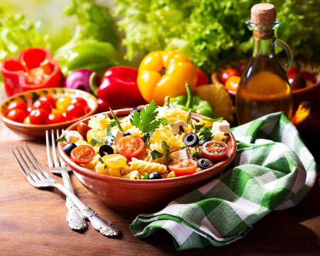 Tazón de fuente de ensalada de pasta con verduras en la mesa de madera