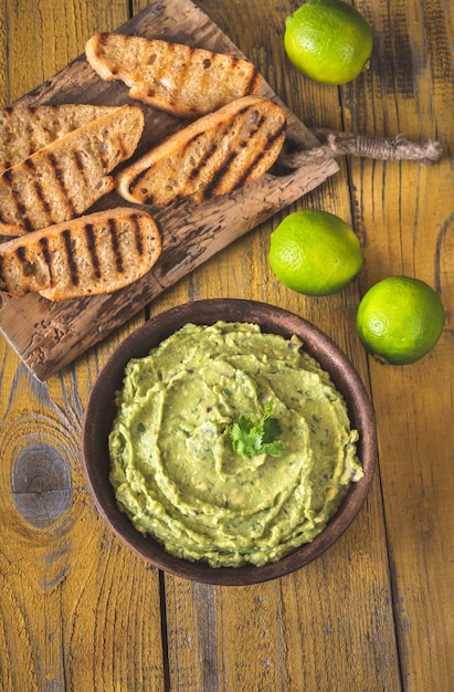 Foto tazón de fuente de guacamole fresco sobre fondo rústico