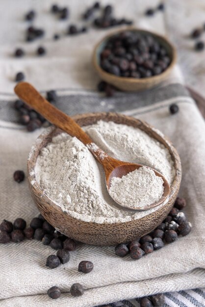 Tazón de fuente de harina de garbanzo negro y frijoles con un primer plano de cuchara de madera sobre mesa de madera blanca. Frijoles tradicionales de Apulia y Basilicata en Italia