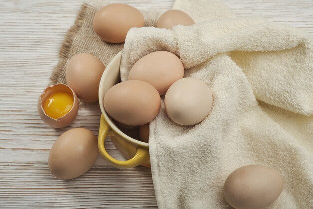 Tazón de fuente de huevos de gallina cruda en el fondo de madera