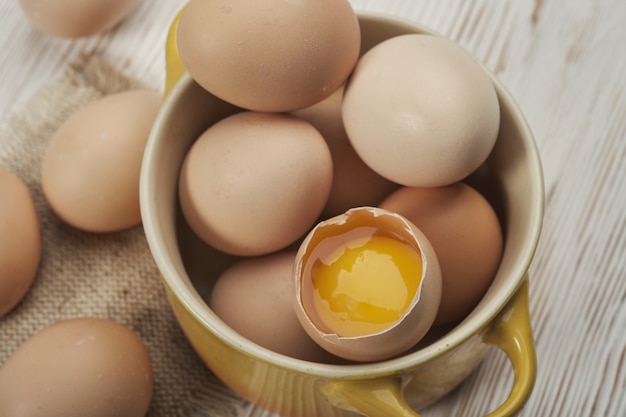 Tazón de fuente de huevos de gallina cruda en el fondo de madera