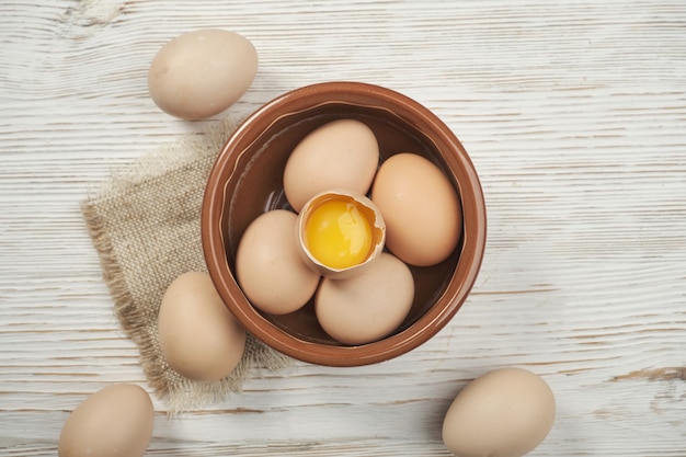 Tazón de fuente de huevos de gallina cruda en el fondo de madera