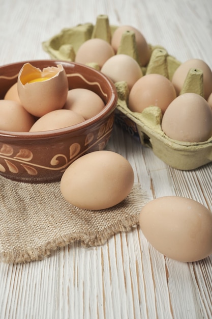 Tazón de fuente de huevos de gallina cruda en el fondo de madera