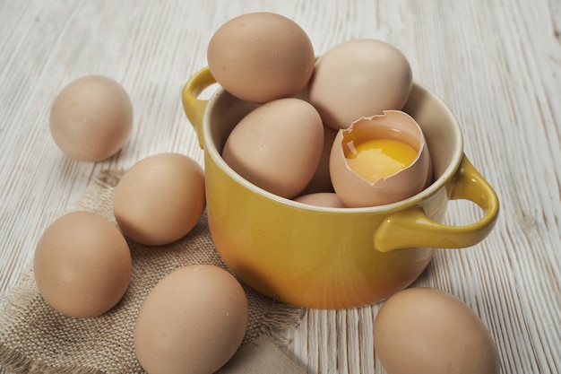 Tazón de fuente de huevos de gallina cruda en el fondo de madera