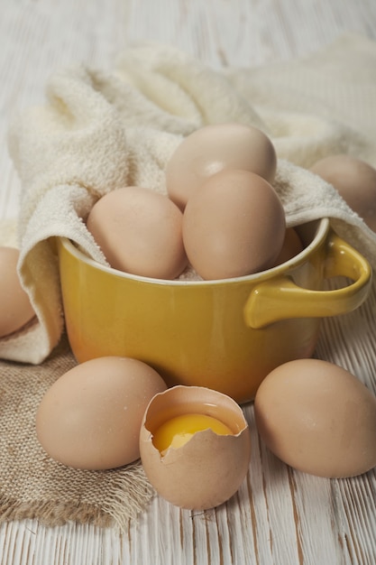 Tazón de fuente de huevos de gallina cruda en el fondo de madera