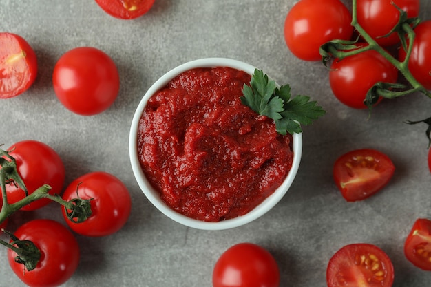 Tazón de fuente de pasta de tomate y tomates sobre fondo de textura gris