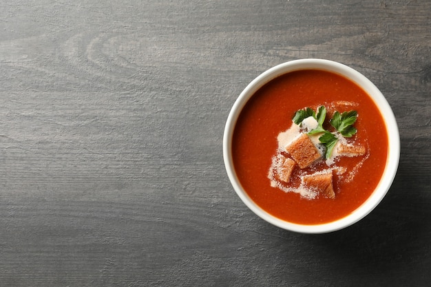 Tazón de fuente de sabrosa sopa de tomate en madera oscura