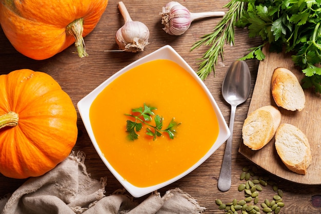 Tazón de fuente de sopa de calabaza con ingredientes para cocinar, vista superior