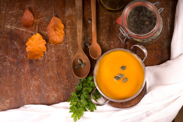 Tazón de fuente de sopa de calabaza sobre fondo de madera rústica.